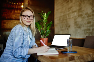 Happy Woman Taking Notes At Table With Open Laptop - BRServ Contabilidade - Controle de caixa: quais os principais erros e como evitá-los?